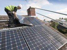 Installer installing solar panels on a roof